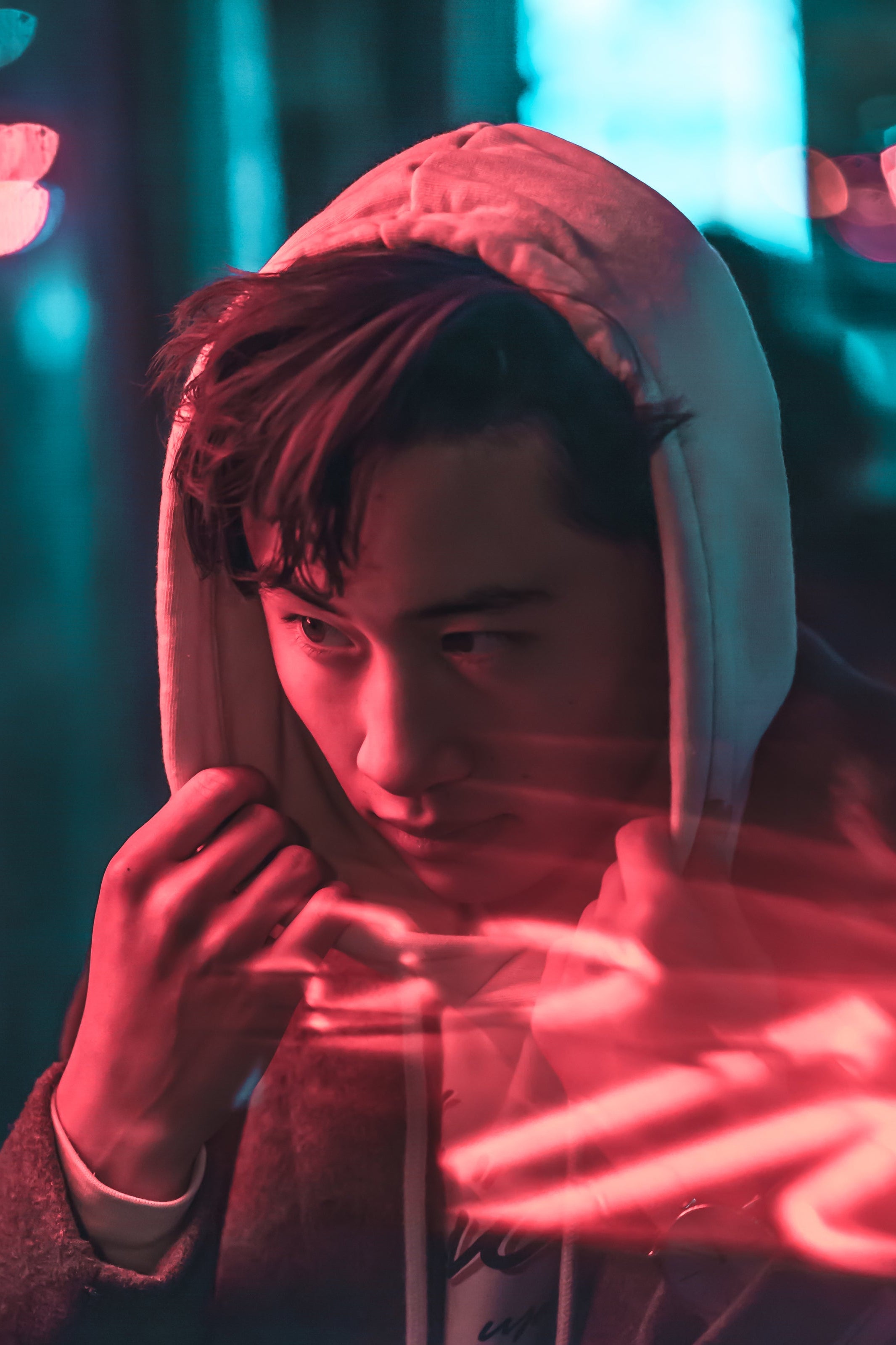 Person wearing a hoodie with neon light effects in a dark setting